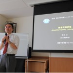 養成講座2回目講師が全体に説明中。講師の右側にはスクリーンありDETのスライドの1ページ目が表示されている